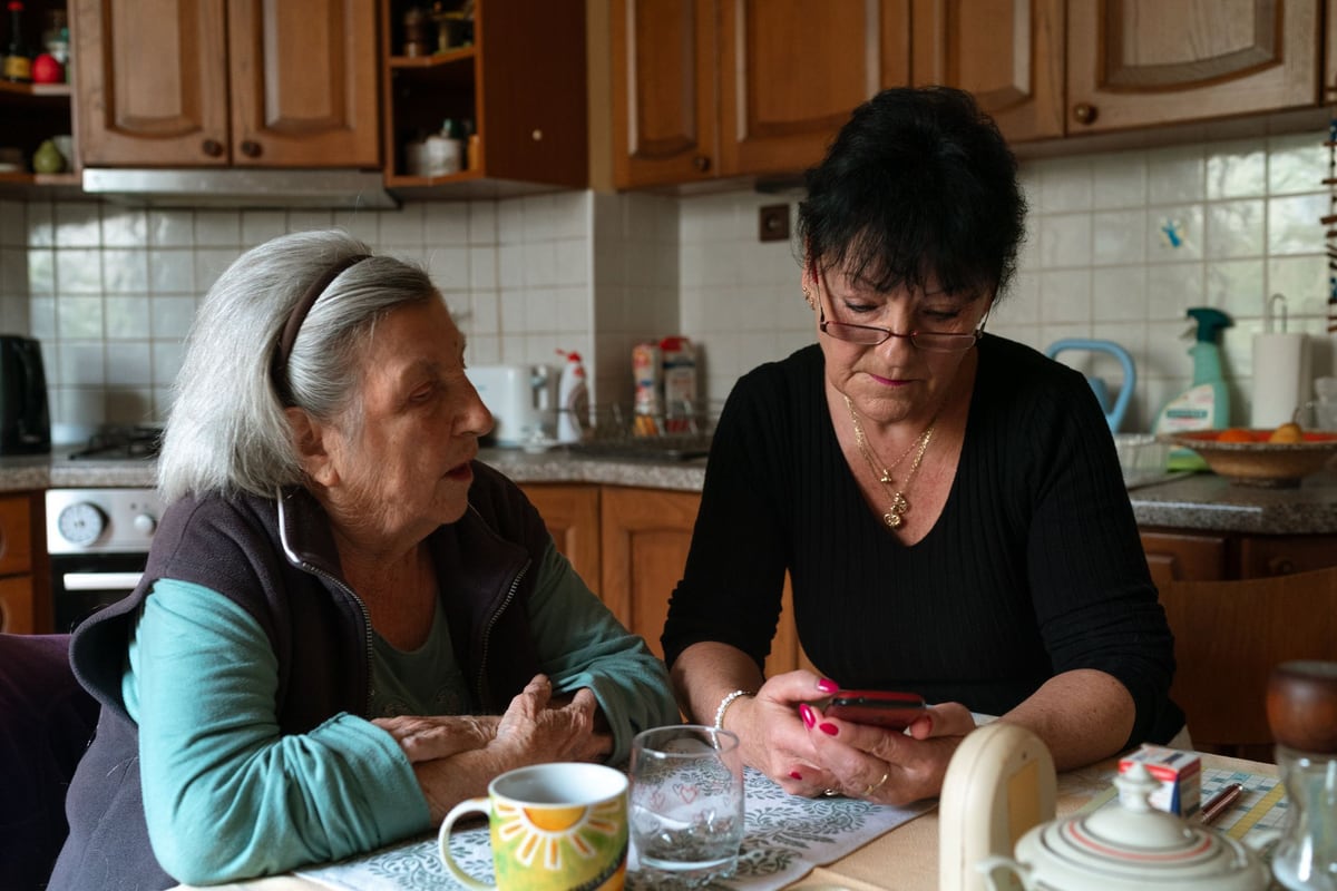 Ältere Dame und Betreuungskraft im Gespräch zu Hause